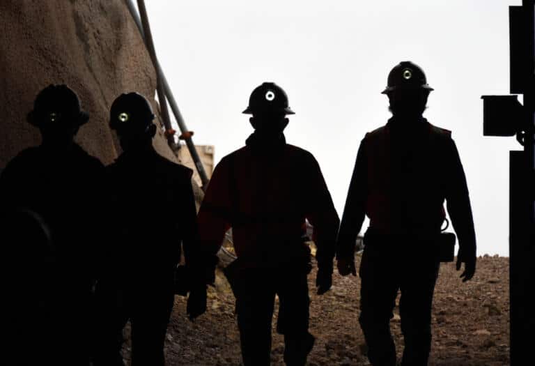 Silhouette Of Miners With Headlamps Entering A Mine